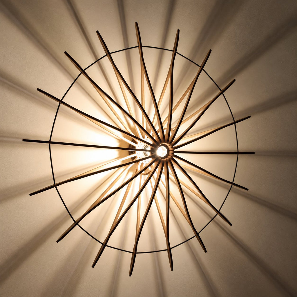 Detail van de verlichte Let’s Twist Again Ø106 wandlamp met houten stroken en schaduwpatroon op de wand.