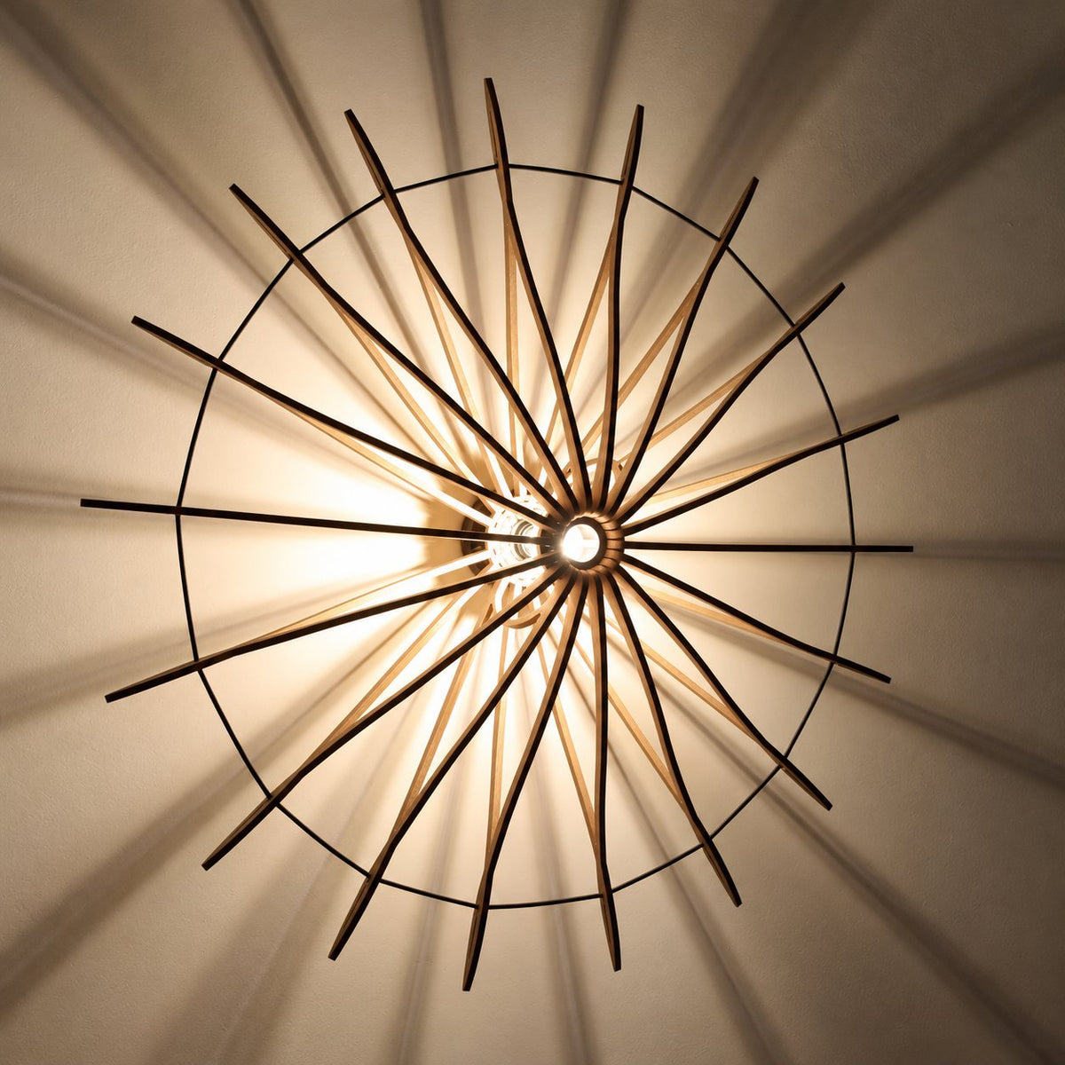 Detail van de verlichte Let’s Twist Again Ø106 wandlamp met houten stroken en schaduwpatroon op de wand.